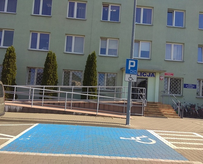 Budynek komendy. Na pierwszym planie miejsce parkingowe dla osób z niepełnosprawnościa