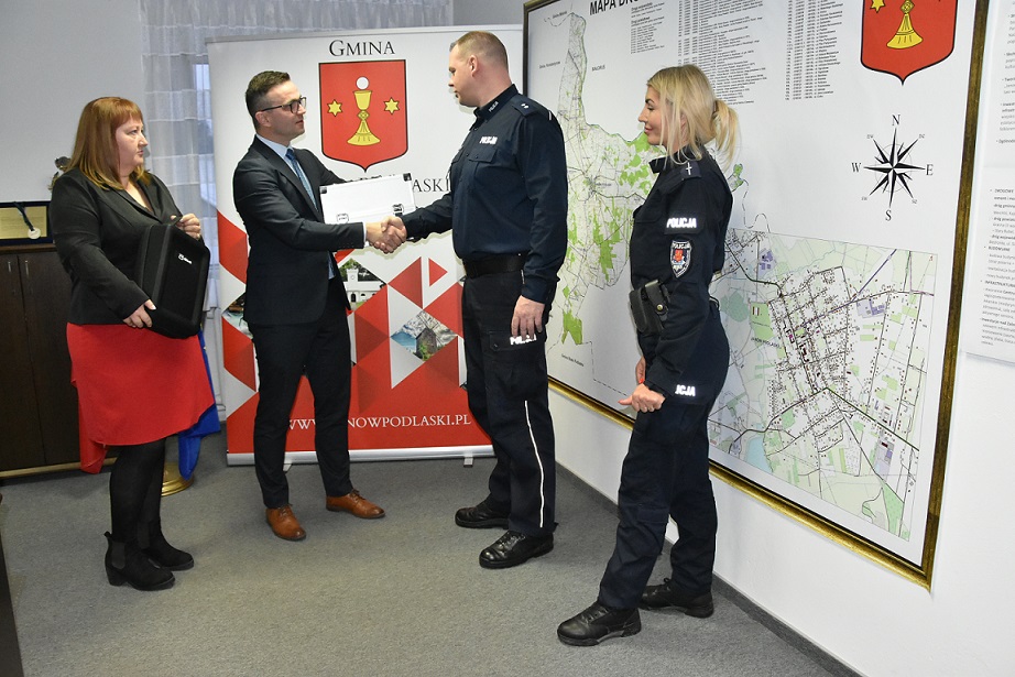 Wójt Gminy przekazuje walizkę Zastępcy Komendanta Komisariatu. Po lewej stronie Przewodnicząca Rady Gminy. Po przeciwnej dzielnicowa