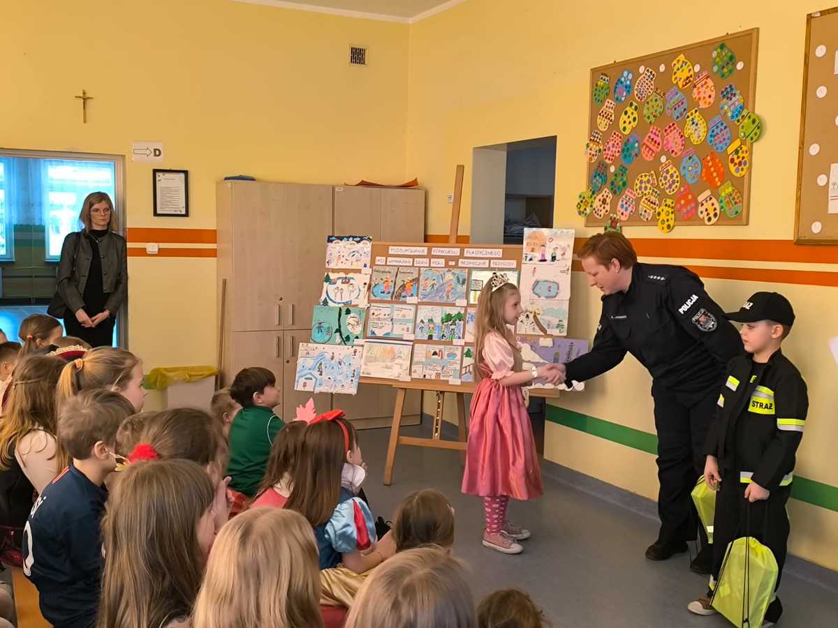 policjantka gratuluje zwycięzcom. Inne dzieci siedzą na ławeczkach