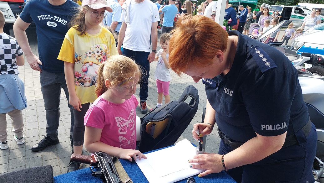 policjantka pokazuje dziecku sposób zabezpieczania linii papilarnych