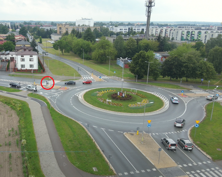 zdjęcie z drona. Ruch w rejonie ronda. Widoczny rowerzysta przejeżdżający przez przejście dla pieszych