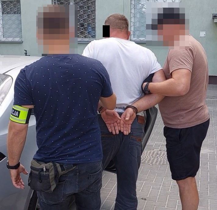 kryminalni prowadzą zatrzymanego do pojazdu 