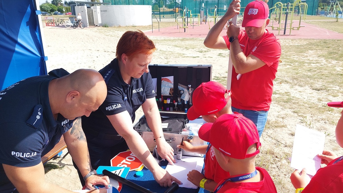 policjanci przy stoisku i dzieci podczas realizacji zadania
