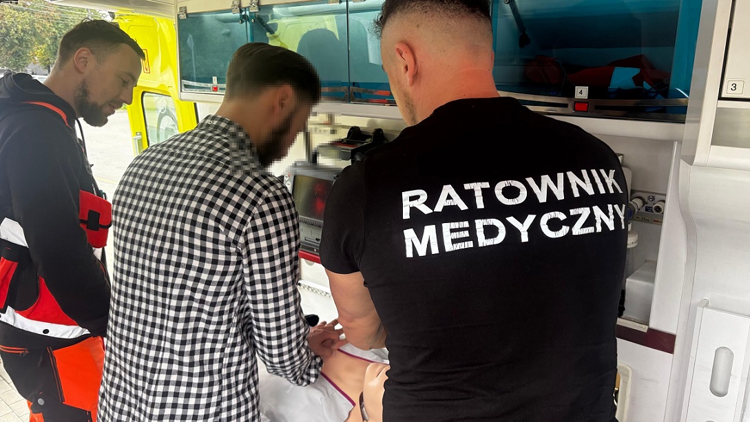 ratownicy i kierowca we wnętrzu auta podczas instruktaru pierwszej pomocy
