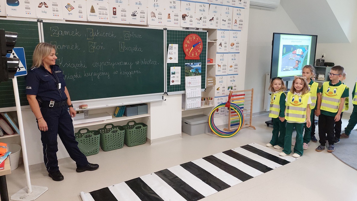 dzieci pod czujnym okiem policjantki przechodzą przez przejście