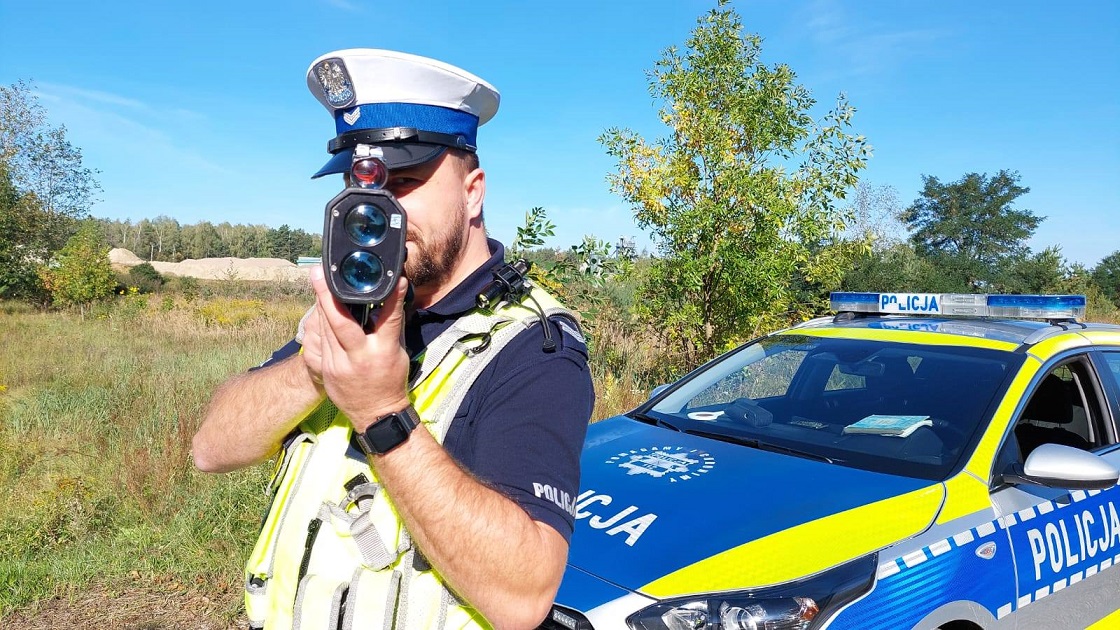 policjant stoi przy radiowozie kontroluje prędkość