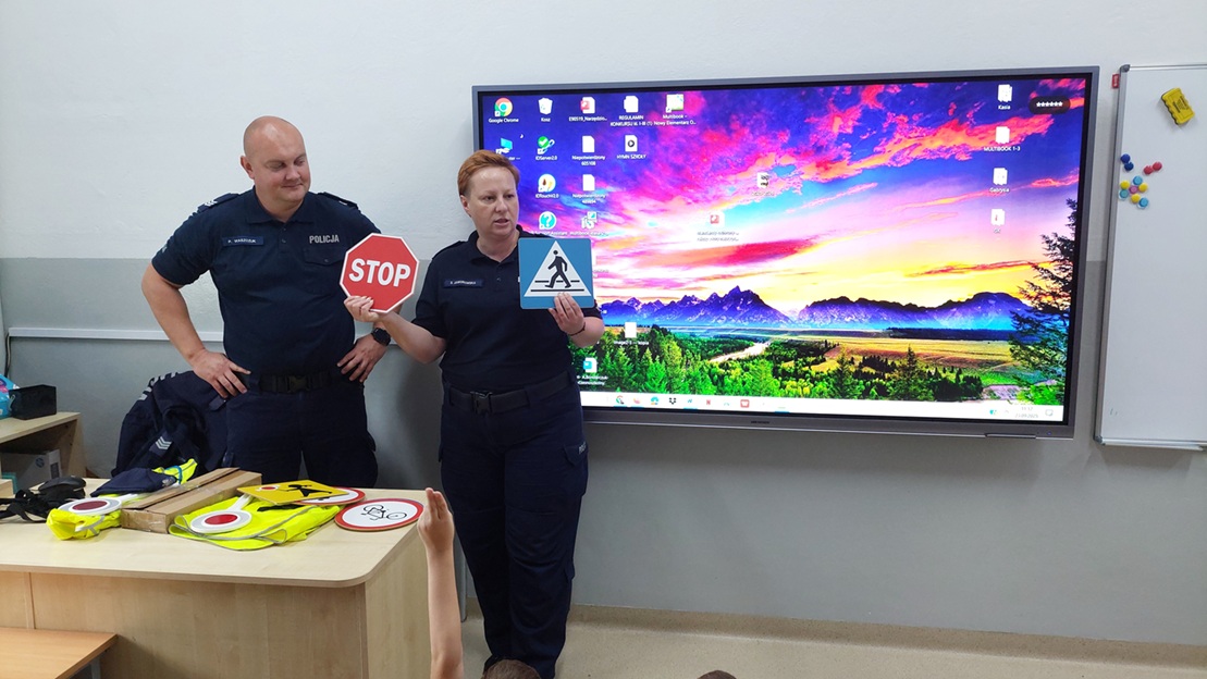 policjanci podczas pogadanki. Policjantka prezentuje znaki drogowe dotyczące pieszych