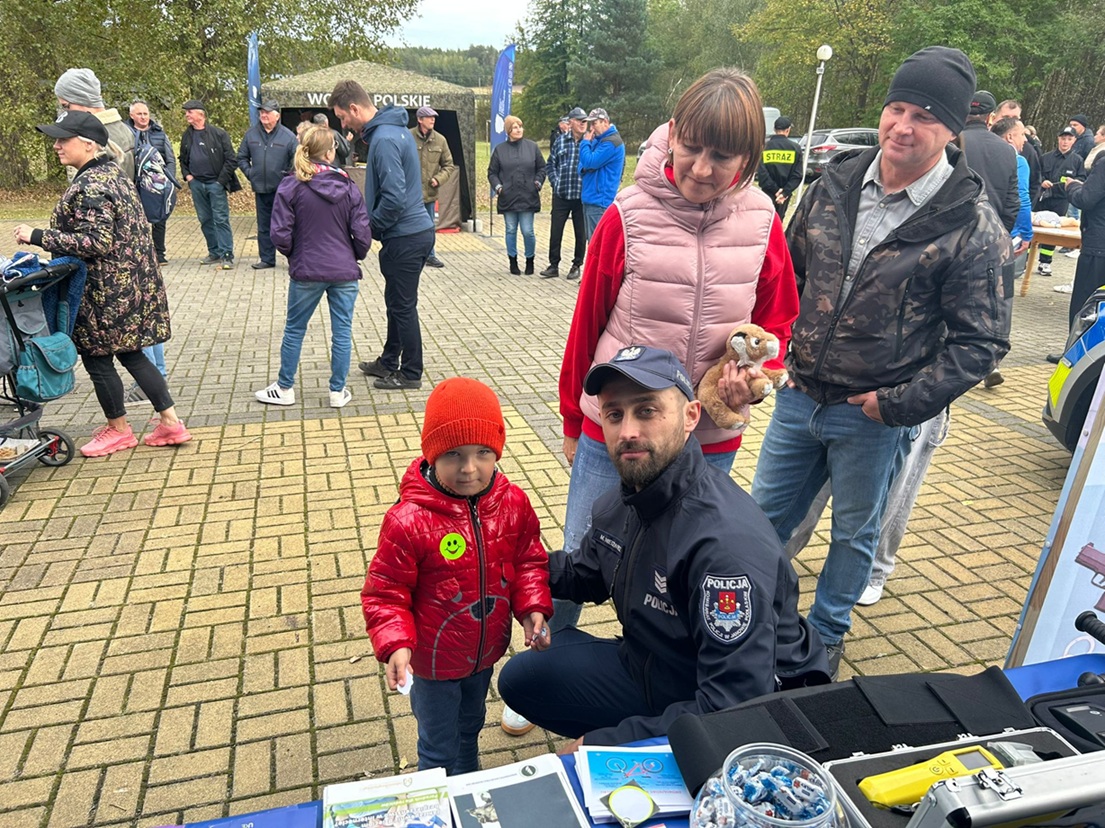 policjant przykucnał obok dziecka przy namiocie