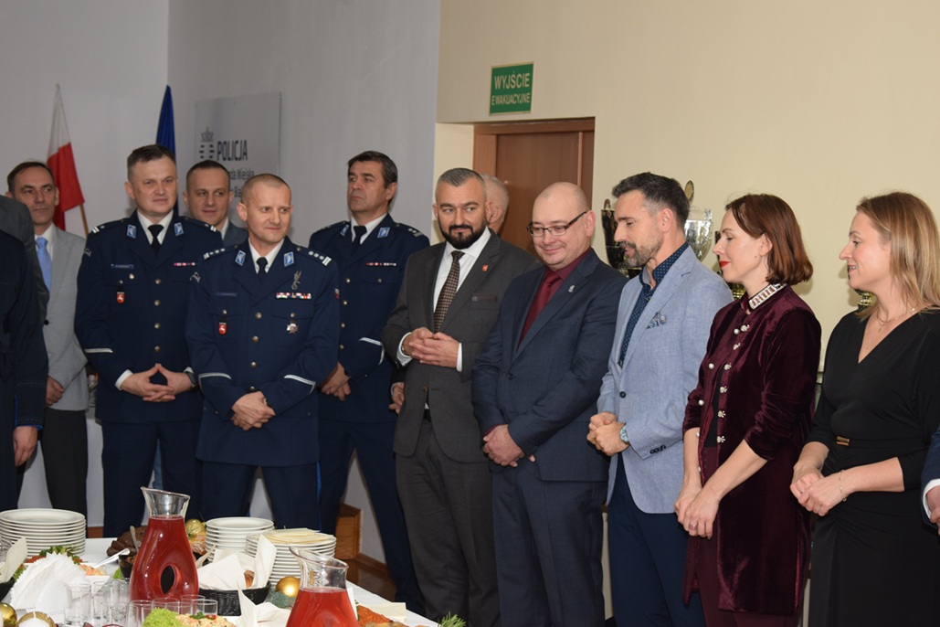 Komendant przemawia podczas wigilii obok zaproszeni goście