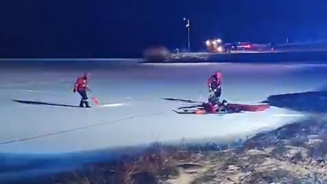 Strażacy wyciągają z zimnego zbiornika wody mężczyznę.