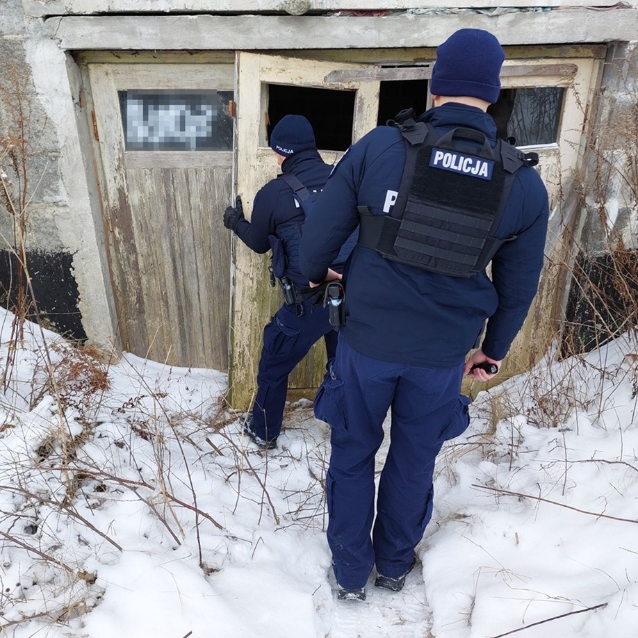 policjant przesuwa drzwi żeby wejść do pustostanu