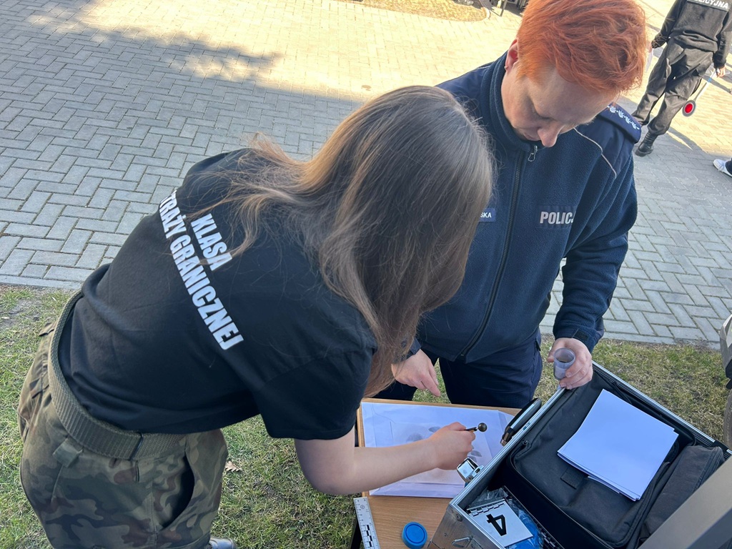 policjantka pokazuje sposób zabezpieczania odbitek linii papilarnych