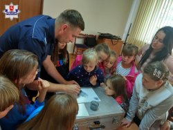 policjant pokazuje dzieciom sposoby zabezpieczania śladów