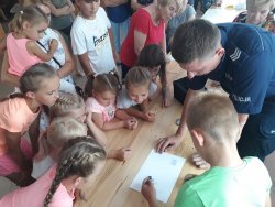 policjant pokazuje sposób zabezpieczania śladów na miejscu zdarzenia