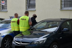 policjanci prowadzą zatrzymanego mężczyznę