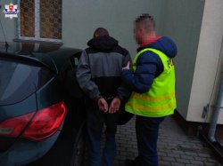 policjant doprowadza zatrzymanego mężczyznę