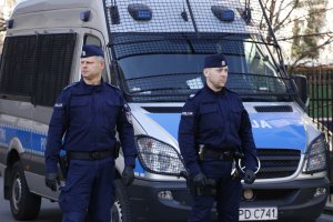 patrol policji, funkcjonariusze stoją obok radiowozu