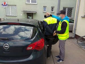 Policjant doprowadza zatrzymanego mężczyznę