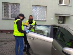 zatrzymana kobieta doprowadzana przez policjanta