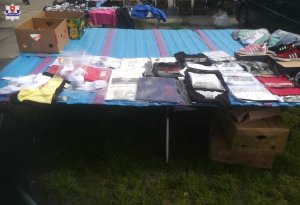 zabezpieczona odzież i obuwie z podrobionymi znakami towarowymi leżąca na stole przeznaczonym do sprzedaży