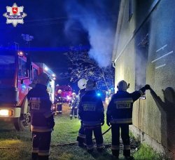 miejsce pożaru oraz strażacy wykonujący swoje działania przed domem