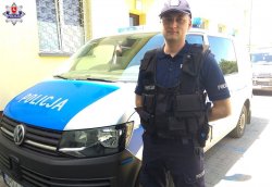 starszy posterunkowy Mateusz Adamiuk stojący przy radiowozie