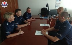kadra kierownicza i nagrodzeni policjanci siedzą przy stole