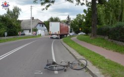 miejsce wypadku drogowego. Leżący na ulicy rower za nim uszkodzony samochód