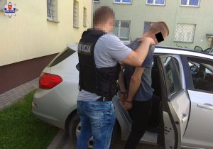 policjant doprowadza zatrzymanego 21-latka