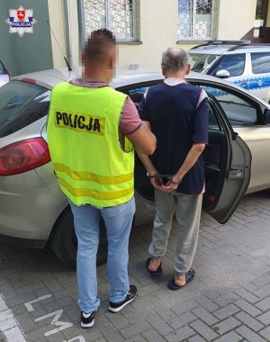 policjant doprowadza zatrzymanego mężczyznę