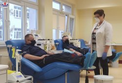 dwaj policjanci leżący na leżankach obok nich stoi pielęgniarka