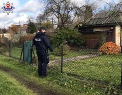 policjant stoi przy ogrodzeniu posesji