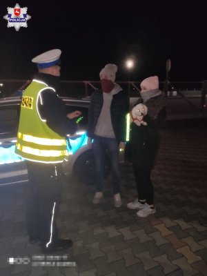 policjant przekazuje elementy odblaskowe pieszym