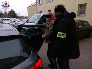 policjant doprowadza zatrzymanego