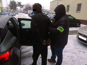 zatrzymany 43-latek doprowadzany przez funkcjonariusza