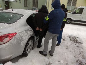 policjanci doprowadzają zatrzymanego
