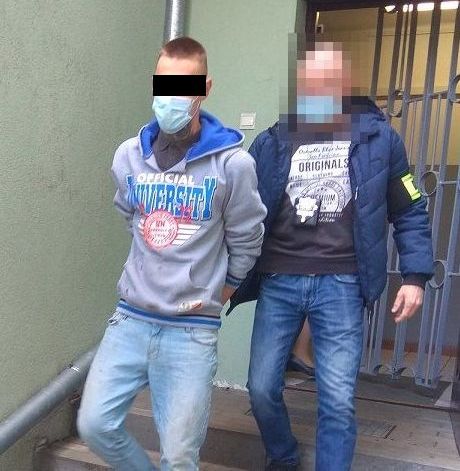 policjant doprowadza zatrzymanego