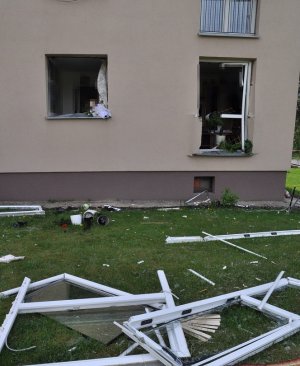 fragment budynku, widoczne wybite okna oraz fragmenty futryn leżące na zewnątrz