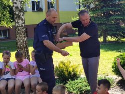 dyrektor i policjant wręczają elementy odblaskowe