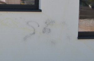 fragment uszkodzonej elewacji widoczne żółte i czarne napisy