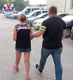 policjant prowadzi zatrzymaną kobietę