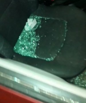 fragmenty wybitej szyby lezące na siedzeniu uszkodzonego samochodu