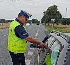 policjant wręcza kierowcy ulotkę