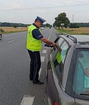policjant wręcza kierowcy ulotkę