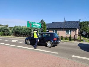 policjant podczas kontroli drogowej stojący przy samochodzie