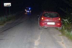 stojący tyłem samochód osobowy marki Alfa Romeo, w tle widoczne radiowozy policyjne