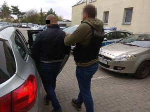 policjant doprowadza zatrzymanego mężczyznę