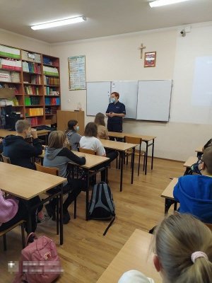 policjantka podczas prelekcji. W ławkach siedzą uczniowie.