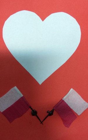 laurka. Na niej białe serce na czerwonym tle. Pod spodem dwie flagi biało czerwone