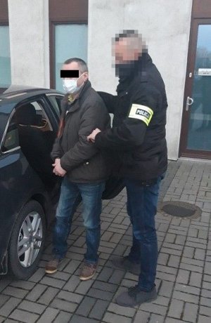 mężczyzna doprowadzany przez nieumundurowanego policjanta